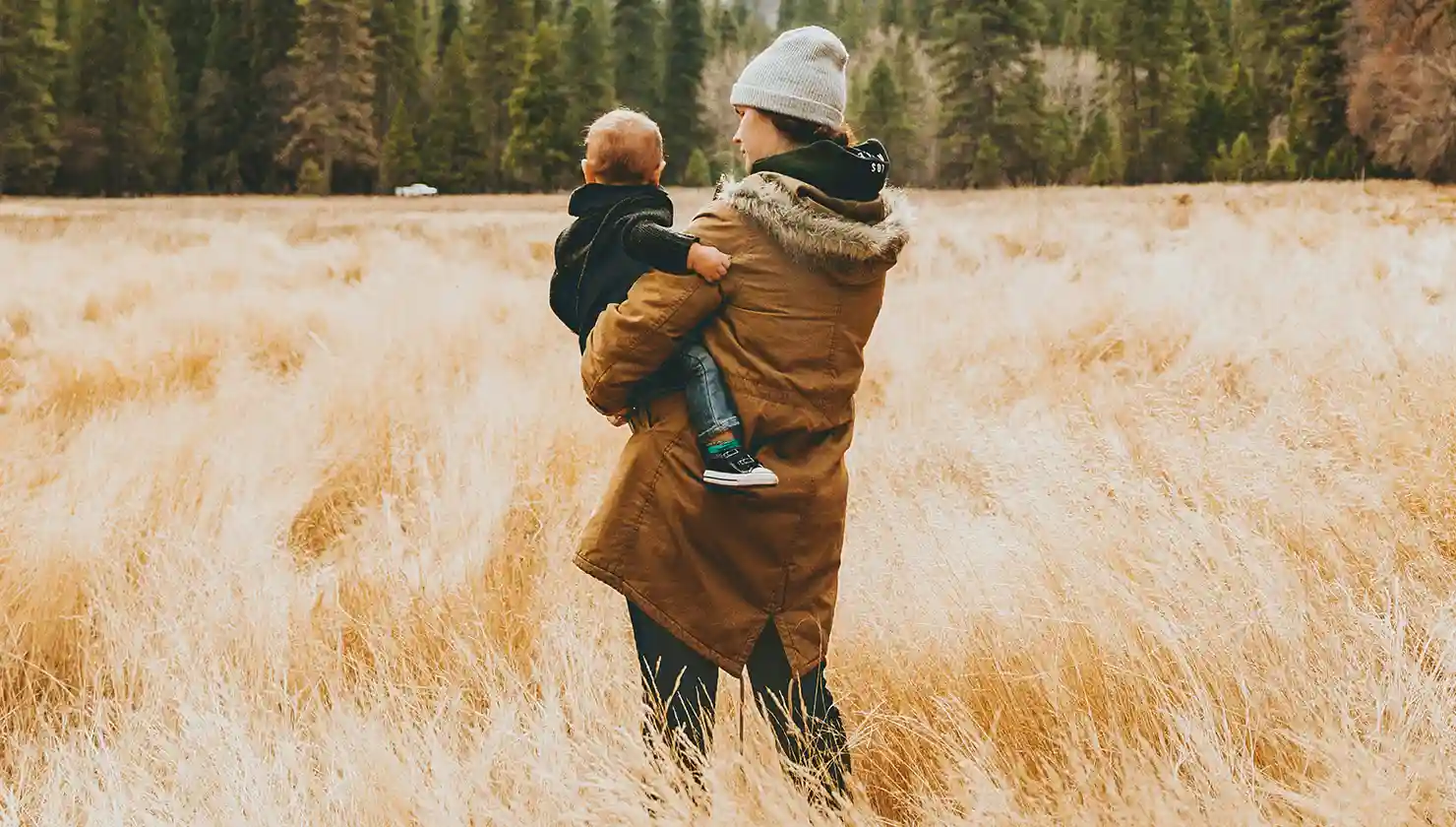 Mother carrying a baby on a walk in fall