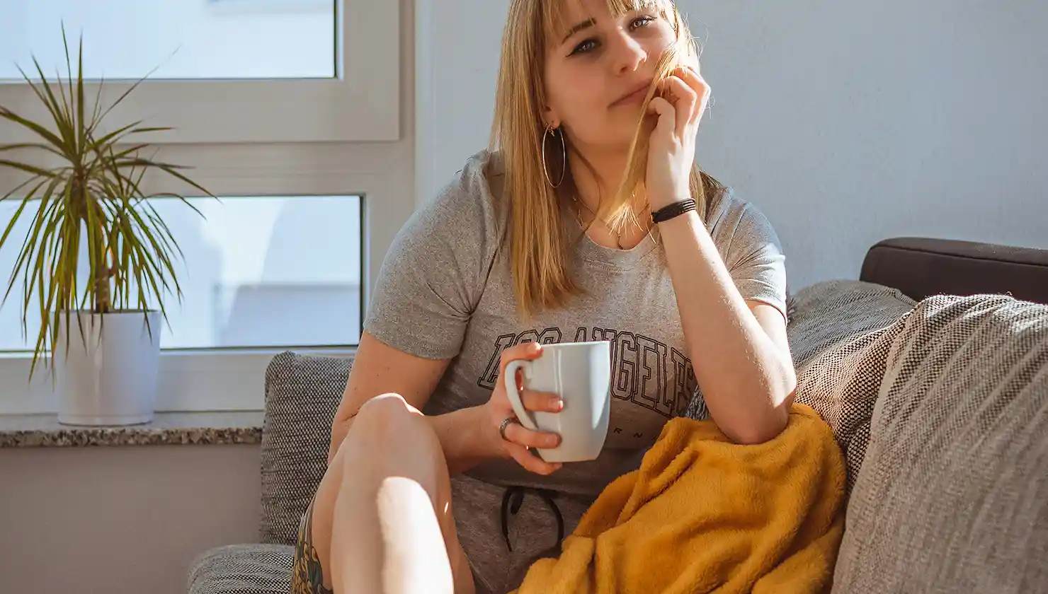 potential plastic surgery patient in recovery woman sitting on couch with mug