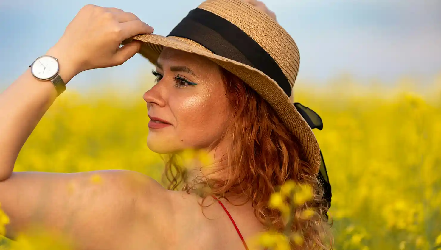 happy woman with a sun hat - might regret waiting for a breast reduction